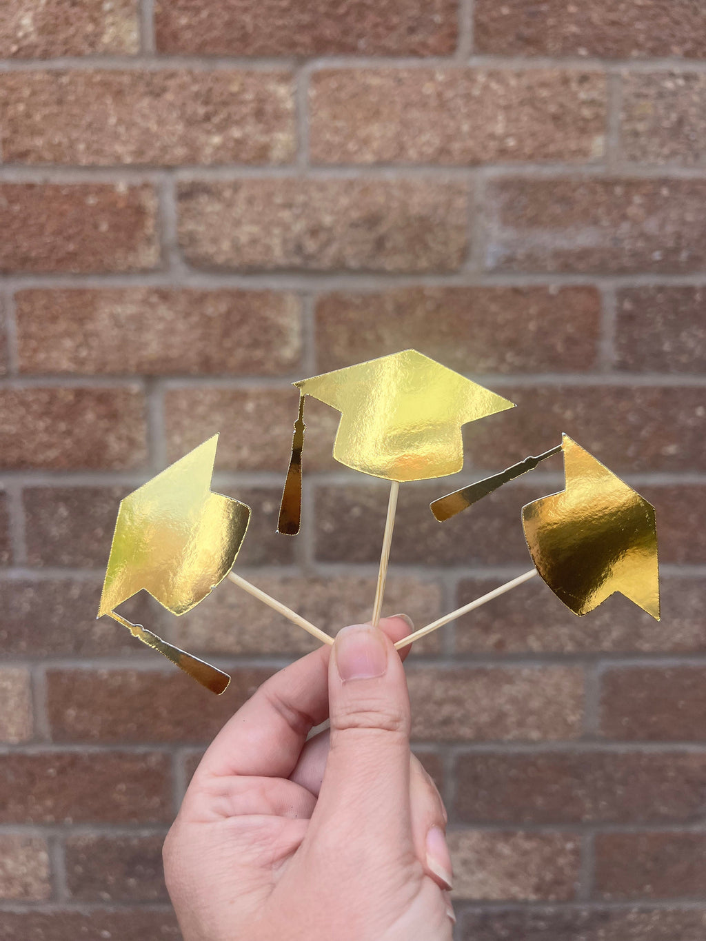 gold shiny graduation cap cupcake toppers on wooden sticks